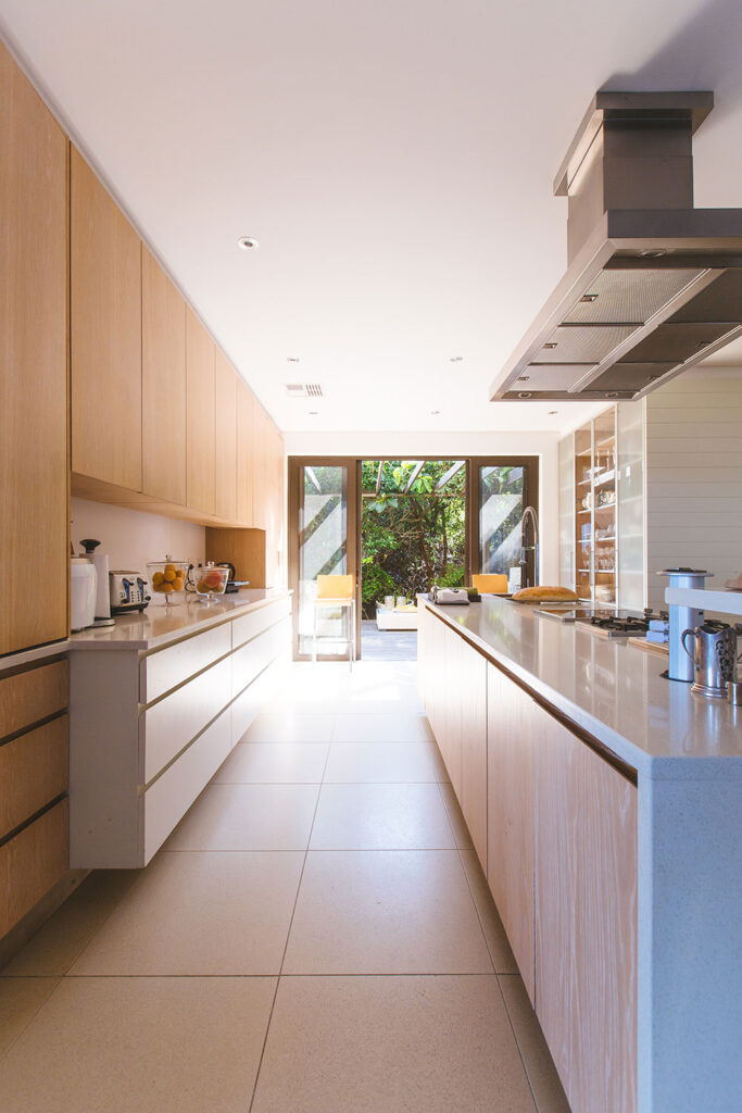 Modern narrow kitchen with wood-and-white cabinetry and a long center island.