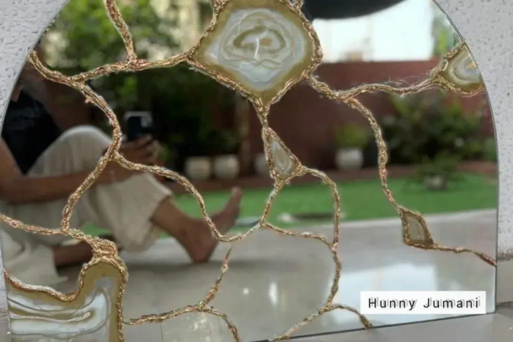 An arched wall mirror decorated with an organic overlay of golden veins and polished agate stone slices.
