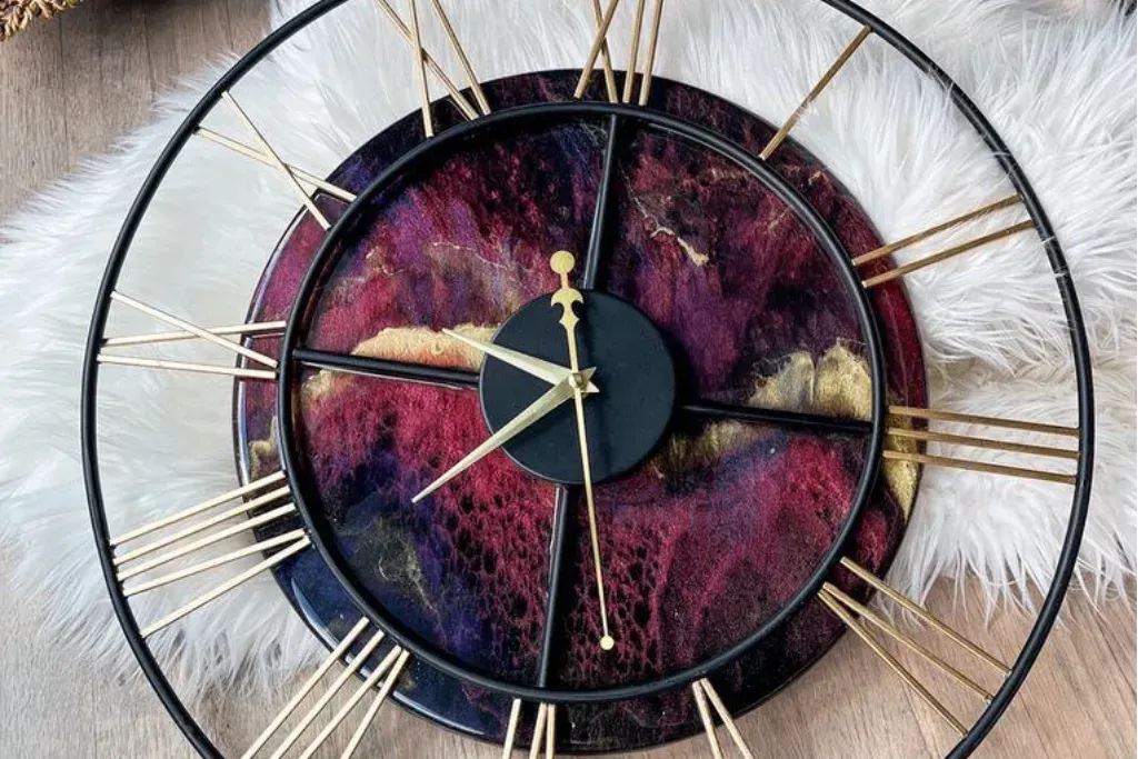 Modern skeleton wall clock with Roman numerals and a swirling burgundy, black, and gold resin face.