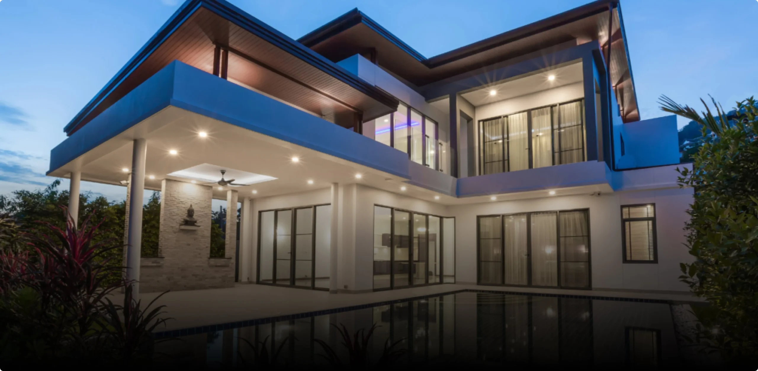 High-end modern home exterior transformation at twilight featuring recessed architectural lighting and a swimming pool reflection.