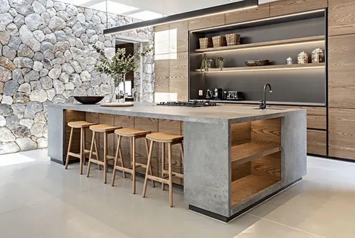 Modern rustic kitchen remodel featuring a large concrete island with wood barstools and a natural stone accent wall.
