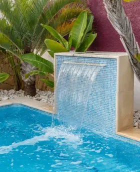 Rectangular backyard swimming pool with brick paver coping and a green lawn.