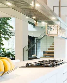 Luxury kitchen design with white island, gas cooktop, and custom glass range hood