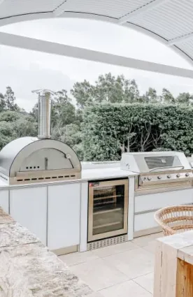 Premium outdoor kitchen with white cabinets and a built-in grill overlooking mountains.