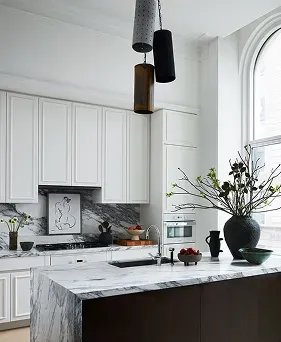 High-end kitchen remodel with marble waterfall island, dark wood accents, and custom white cabinets